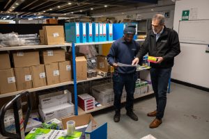 Chrisbeon team members discussing office furniture and delivery planning inside the warehouse at their Telford premises.